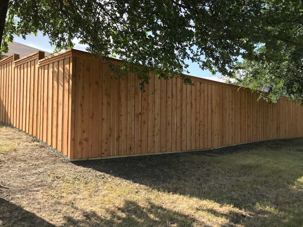 Wooden privacy fence along a grassy yard under a leafy tree