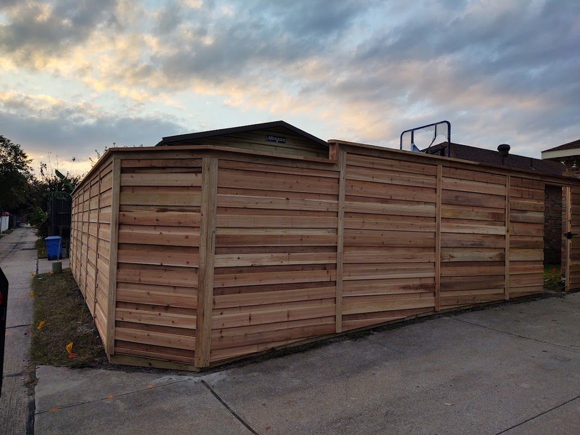 Wooden privacy fence around a corner lot at dusk, with a cloudy sky overhead.