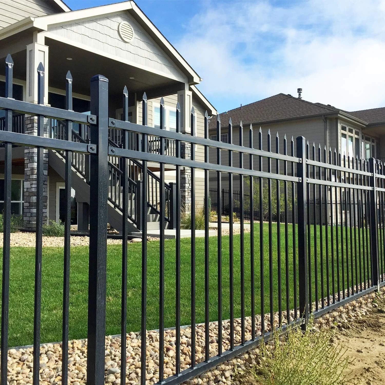 Black metal fence in front of apartment buildings and a grassy courtyard