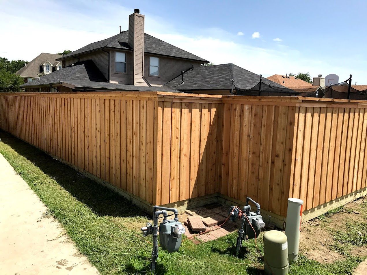 Wooden privacy fence around a suburban yard and house under a sunny sky