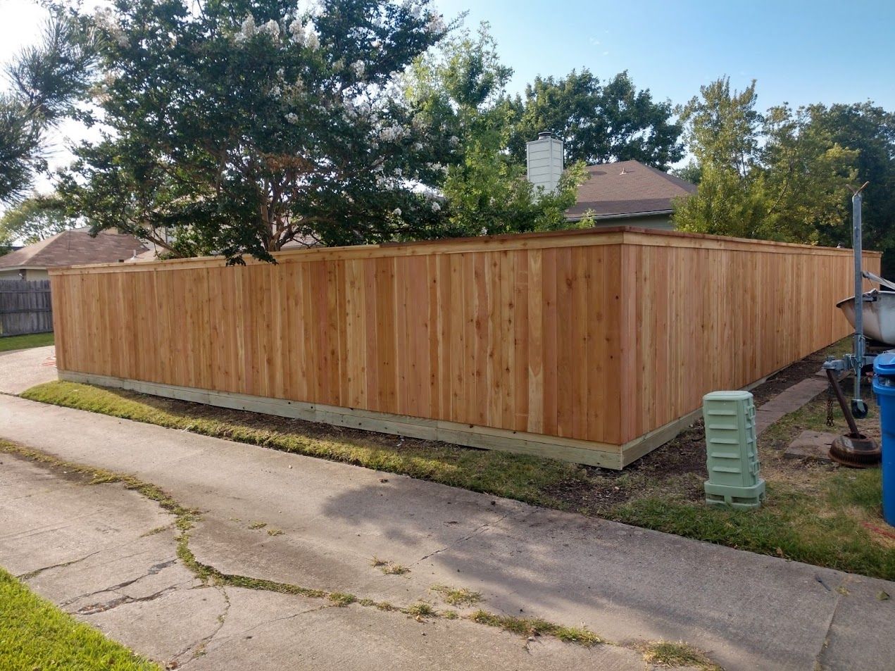 Wood privacy fence along a driveway in a suburban neighborhood