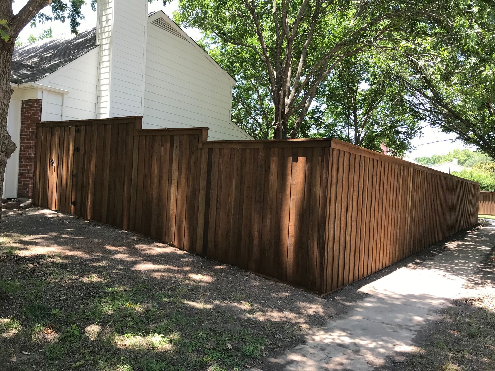 Wooden fence surrounding a white house in a shaded yard