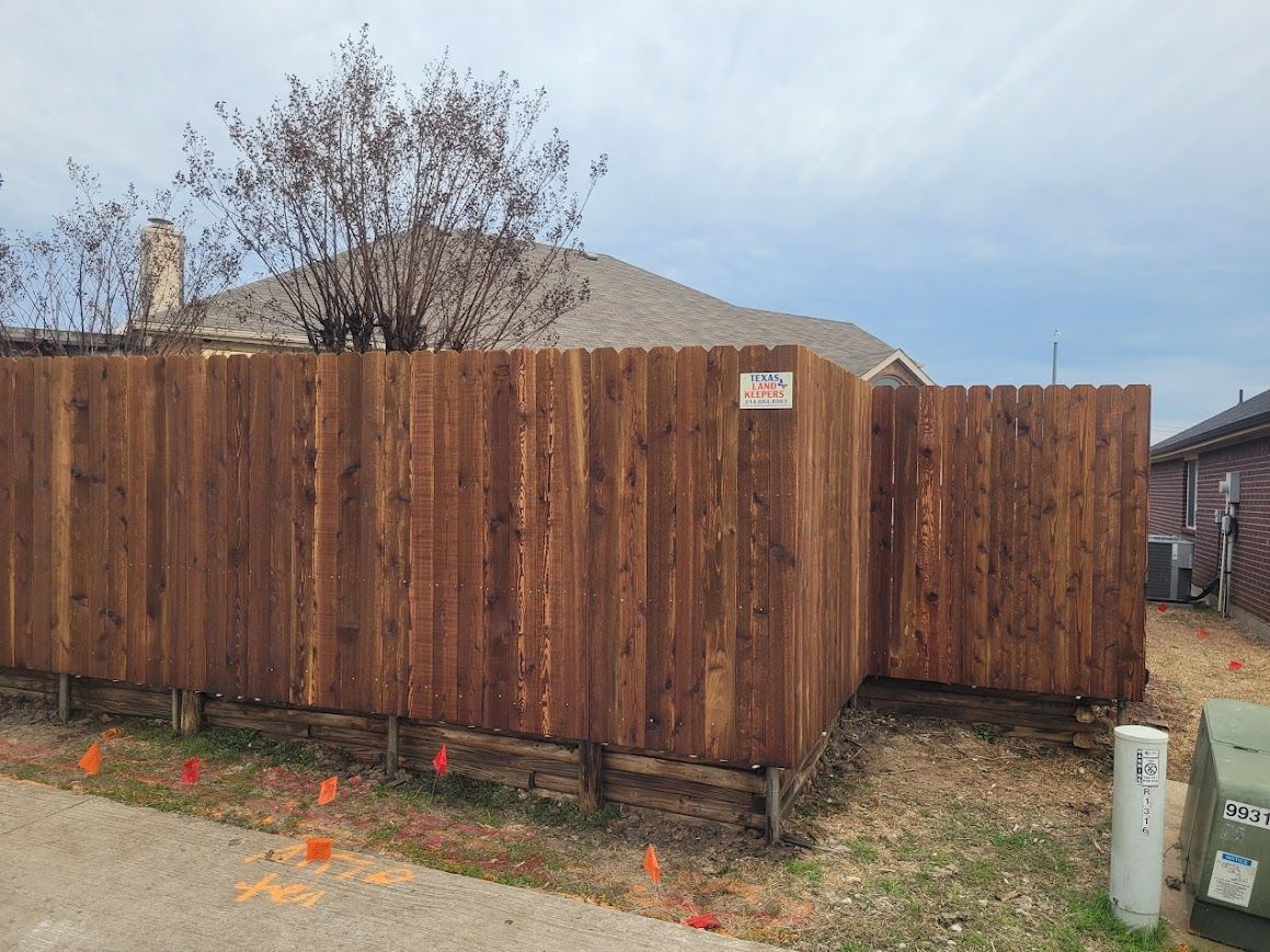 Wooden privacy fence around a yard with a tree and cloudy sky overhead