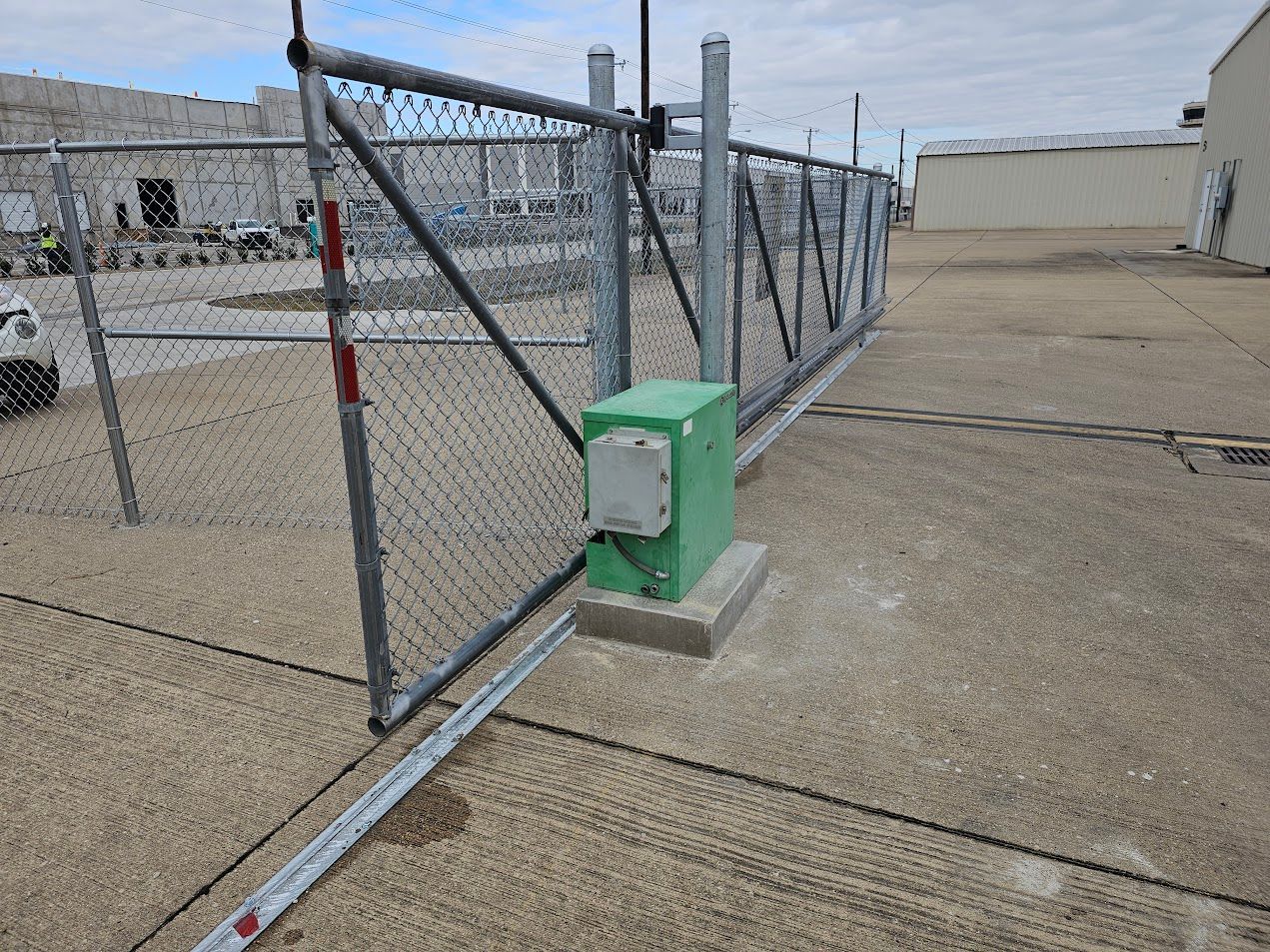 Green gate motor beside a chain-link security fence on a concrete industrial lot.
