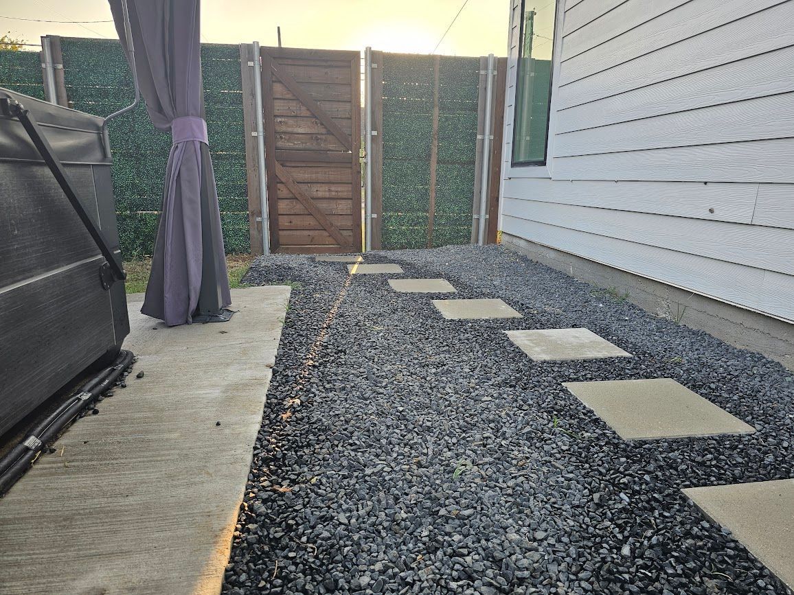 Narrow gravel side yard with stepping stones, fence, gate, and house exterior wall