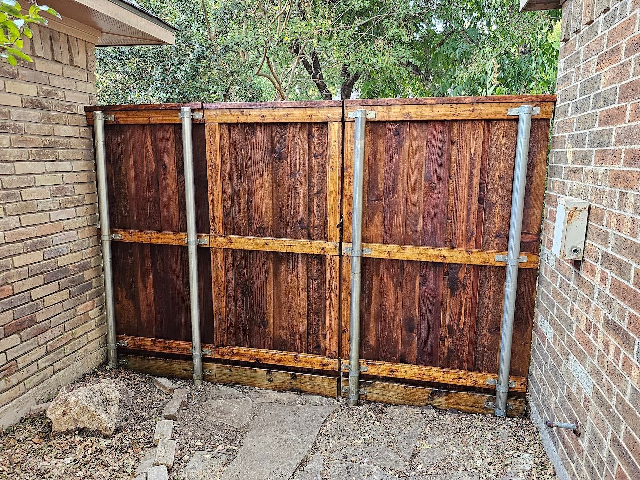 Rustic wooden double gate between brick walls in a narrow outdoor passage.