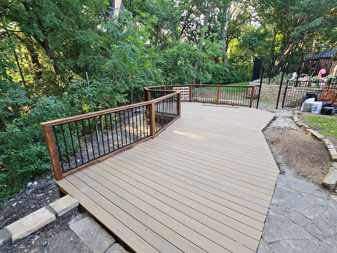Wooden boardwalk ramp with black railings winding through a leafy wooded park.