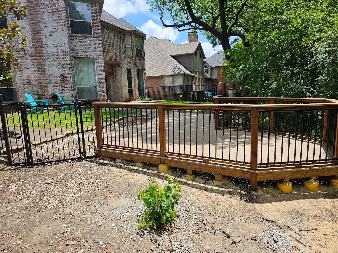 Wooden ramp with railing beside a stone building in a shaded outdoor courtyard.