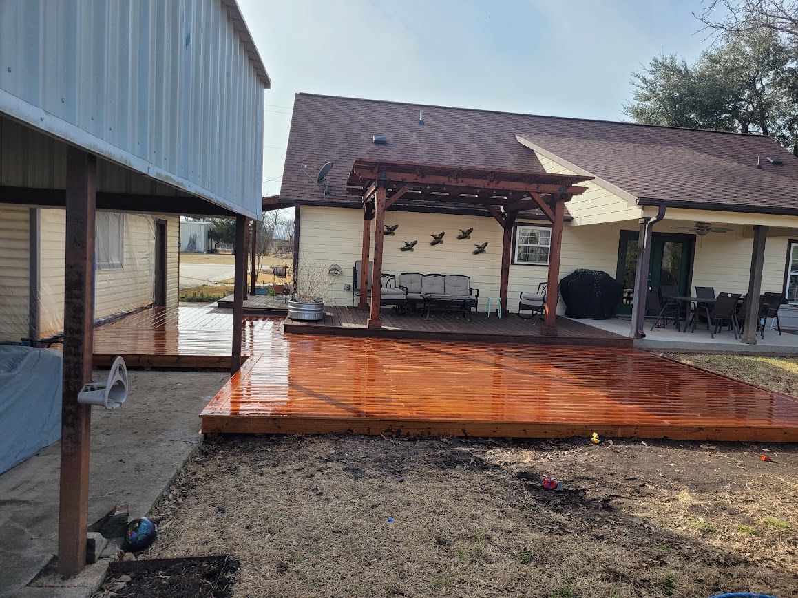 Rain-soaked wooden patio with a small covered gazebo and adjacent house porch.