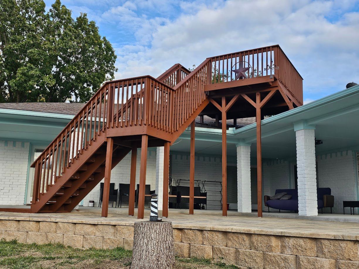 Wooden staircase and raised deck attached to a house with a blue roof under a partly cloudy sky