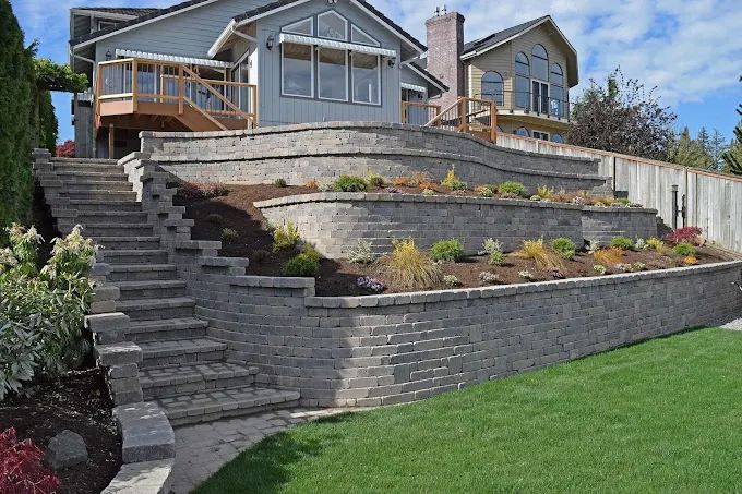 House with terraced stone retaining walls and staircase on a landscaped hillside