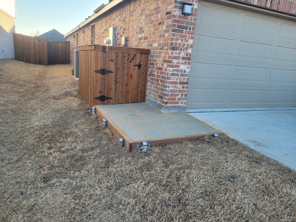 Backyard side yard with garage, concrete step, wooden utility box, and dry grass path