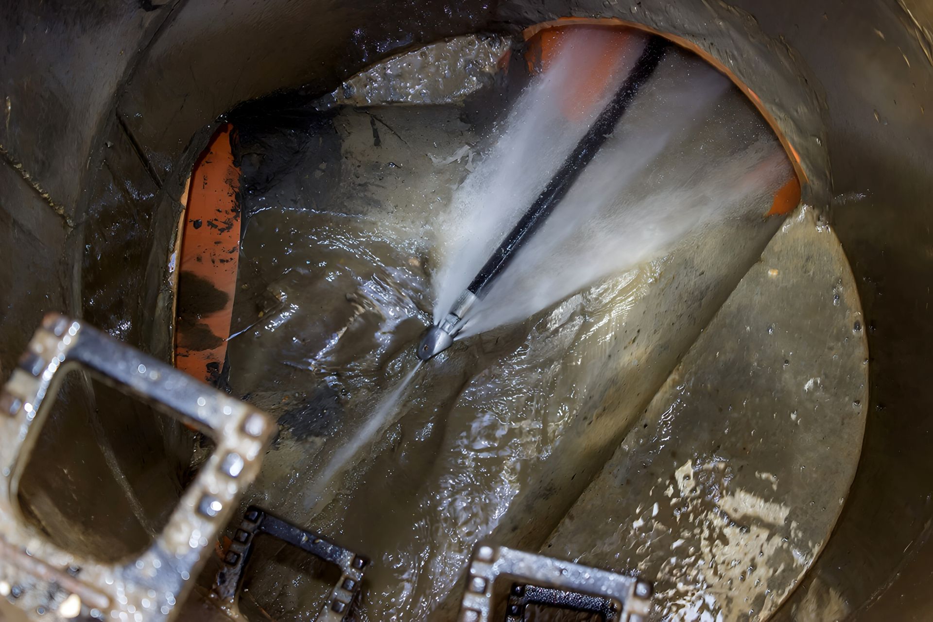 Close-up of a metal tank interior with reflective liquid and pipes or hoses entering through an opening