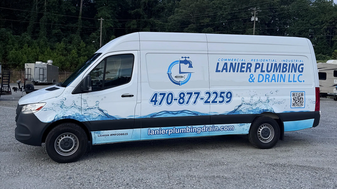 White Lamier Plumbing & Drain LLC van with blue logo and phone number parked outdoors.