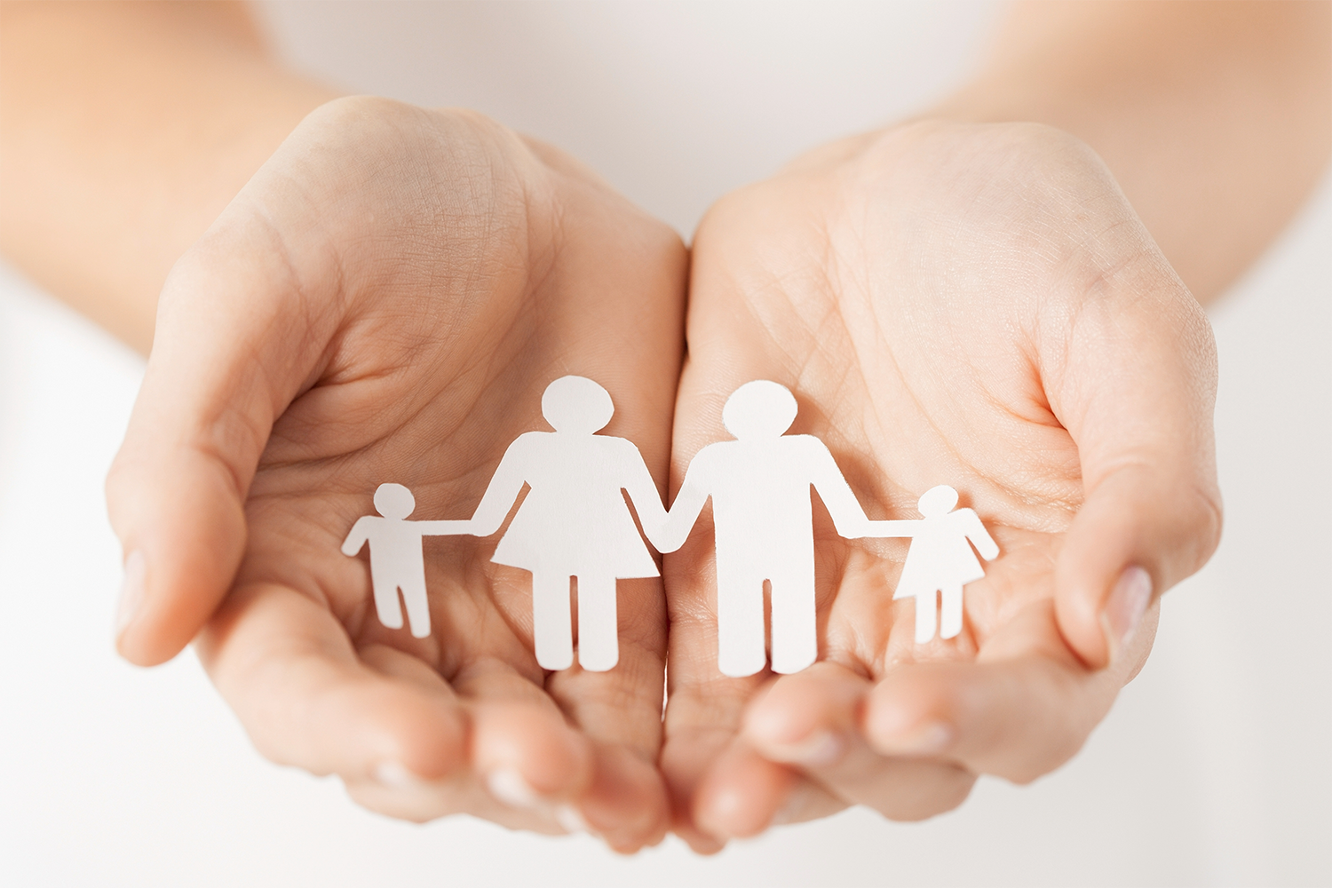 A person is holding a paper cut out of a family in their hands.