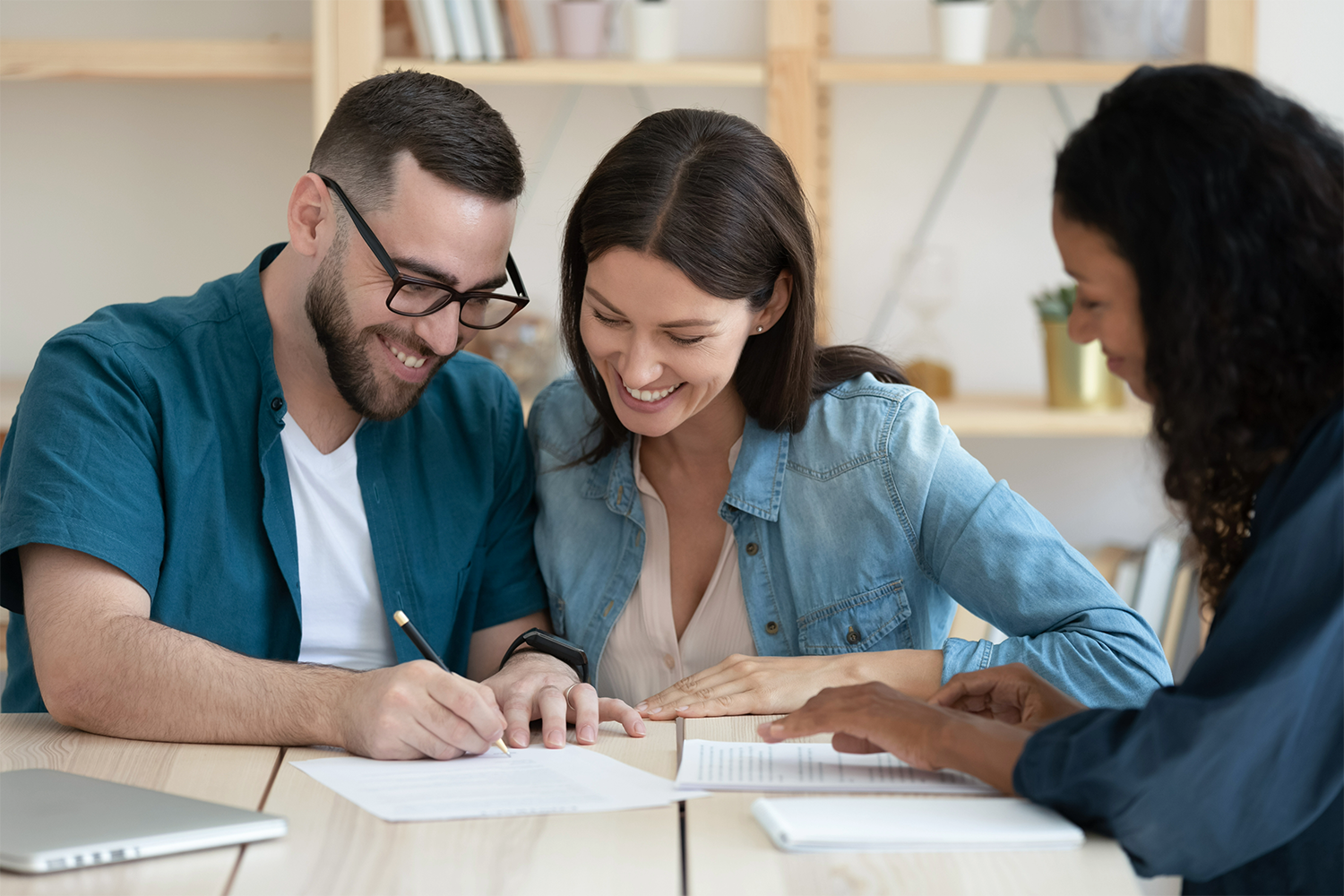 A man and a woman are sitting at a table signing a document.