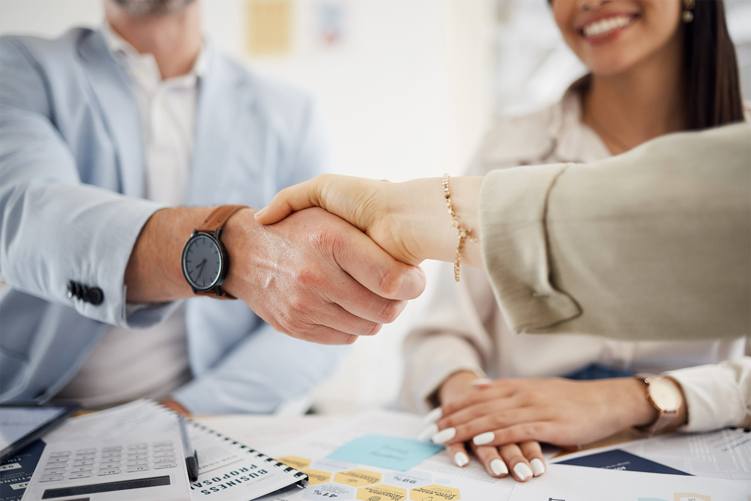 A man and a woman are shaking hands over a table.