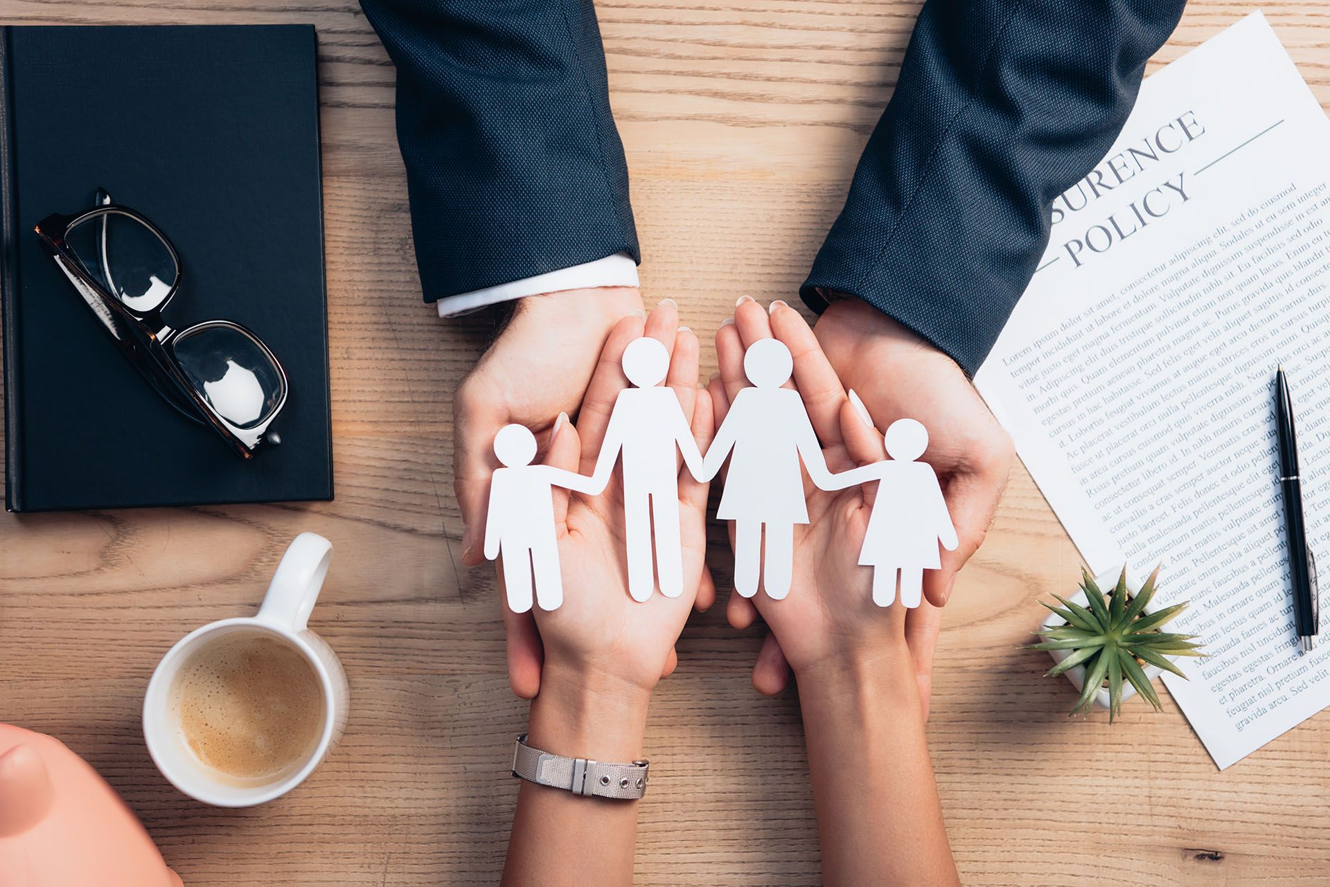 A man and a woman are holding paper cutouts of a family in their hands.