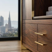 Wooden cabinet with brass handles beside a window overlooking a blurred city skyline.