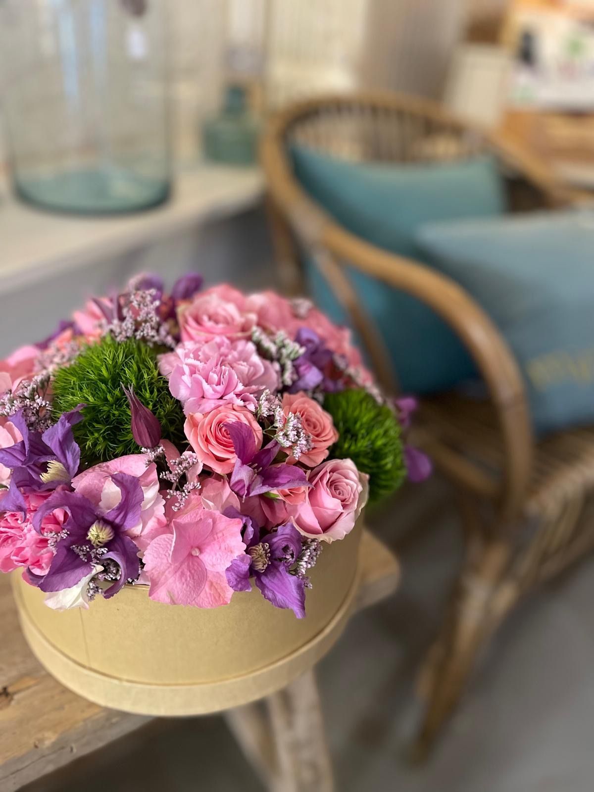 Une femme tient une boîte ronde remplie de fleurs roses.