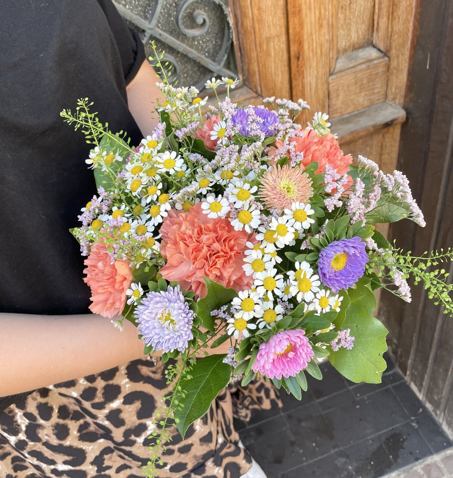 Une femme en jupe à imprimé léopard tient un bouquet de fleurs