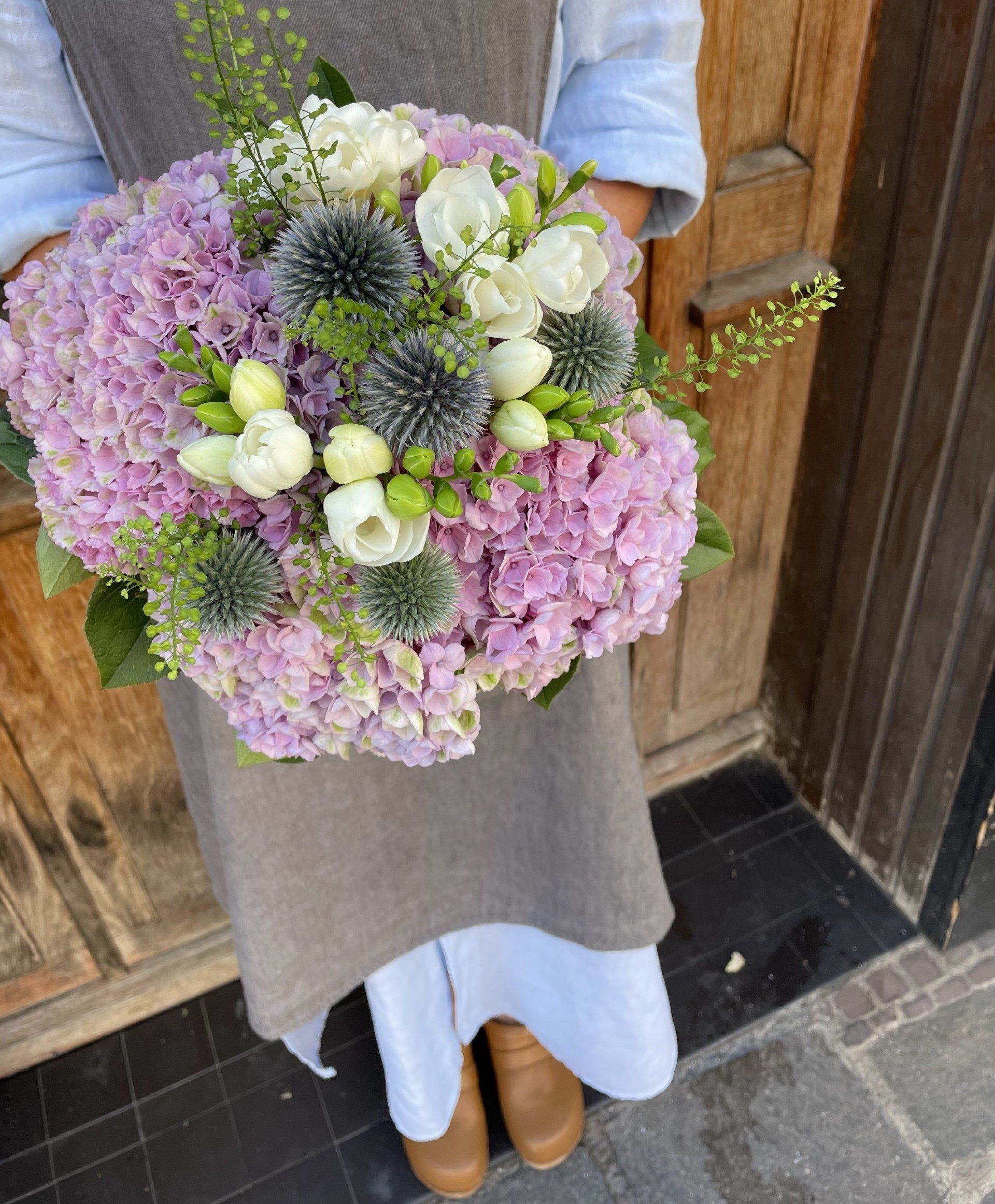 Une femme tient un bouquet de fleurs roses et blanches.