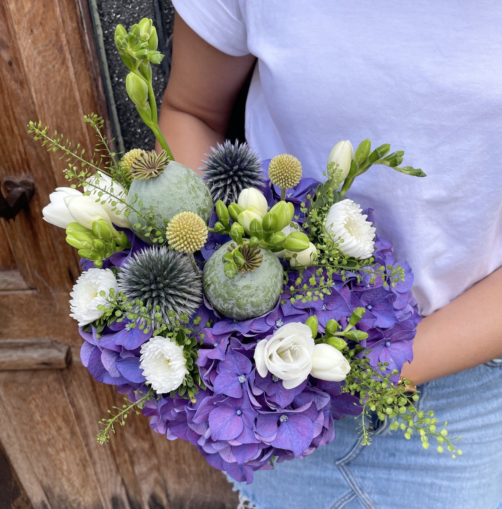 Une femme tient un bouquet de fleurs violettes et blanches