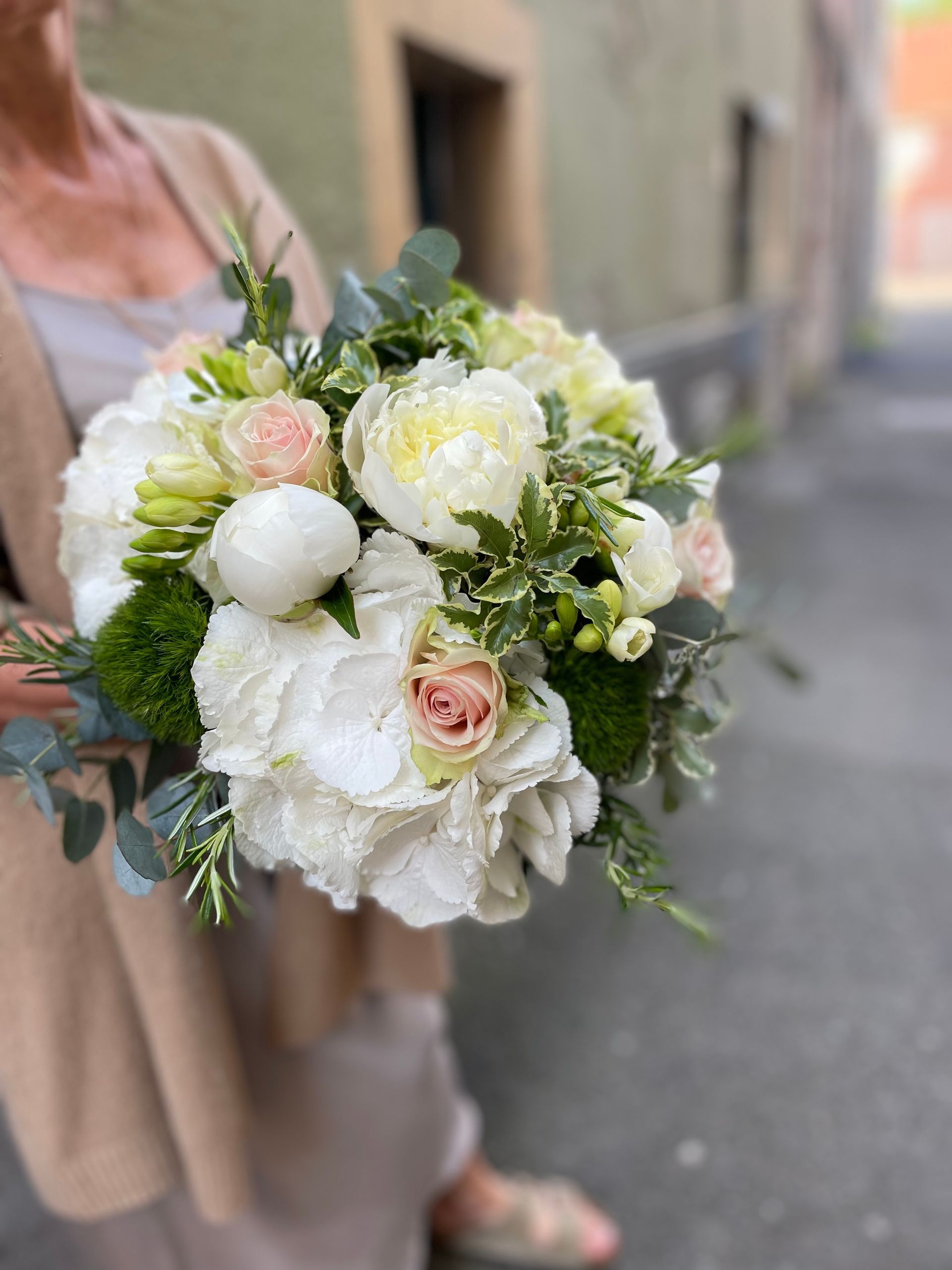Une femme est assise à une table tenant un bouquet de fleurs blanches.