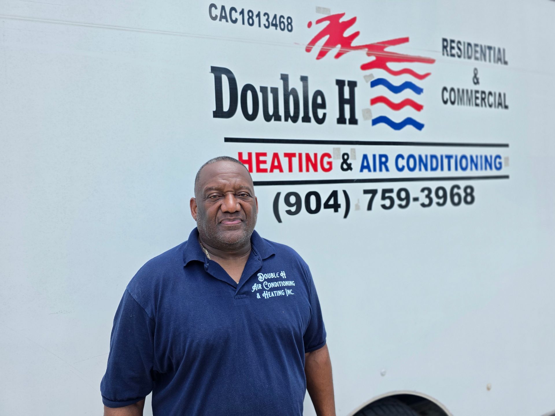 Man in blue shirt smiles in front of a white van with