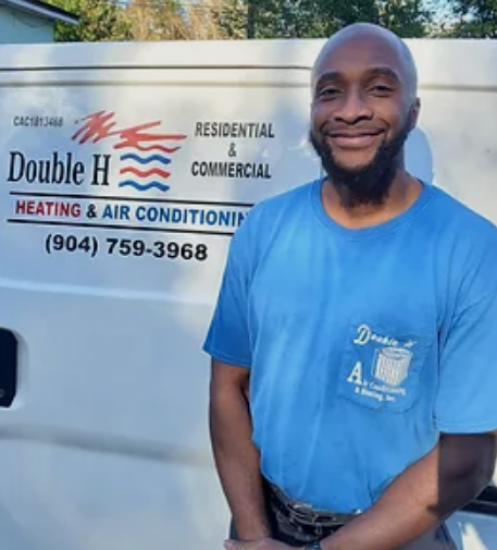 Man in blue shirt smiles in front of a white van with