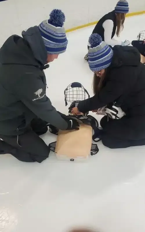 People kneeling on snow, adjusting a sled or equipment around a small animal carrier.