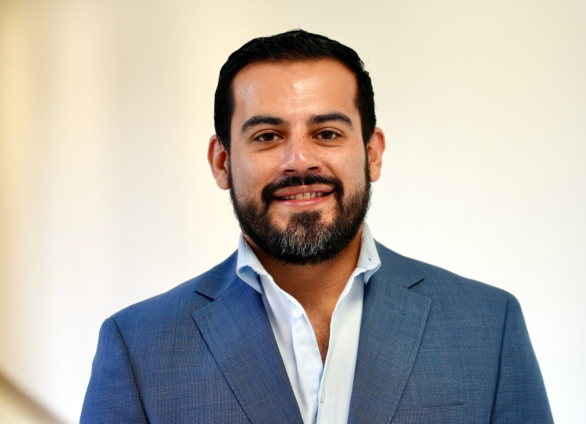 Smiling man in a blue blazer and white shirt against a light background
