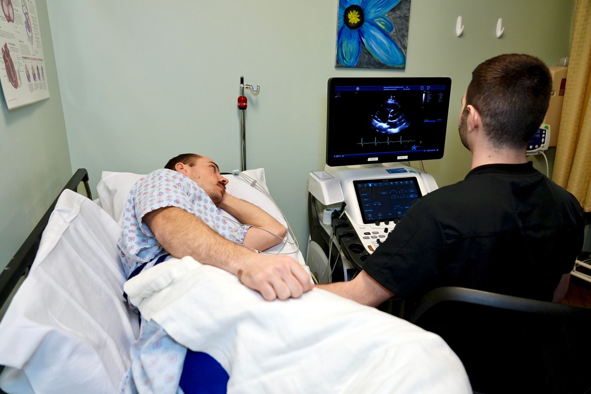 Patient lying on exam bed while a clinician performs an ultrasound in a medical room