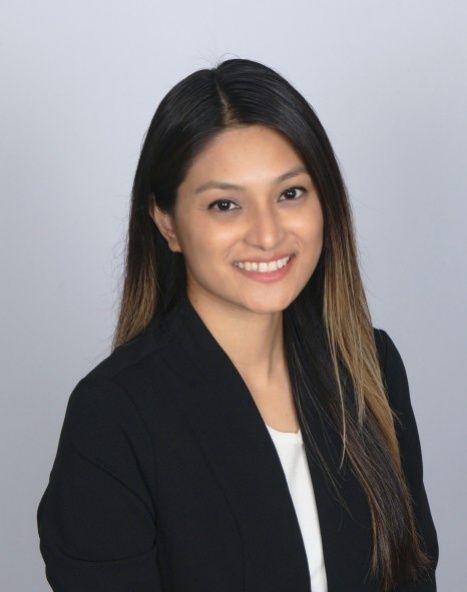 Portrait of a smiling woman in a black blazer against a light gray background