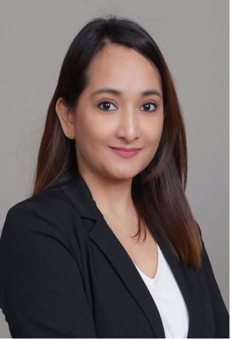 Portrait of a smiling woman in a black blazer and white top against a gray background