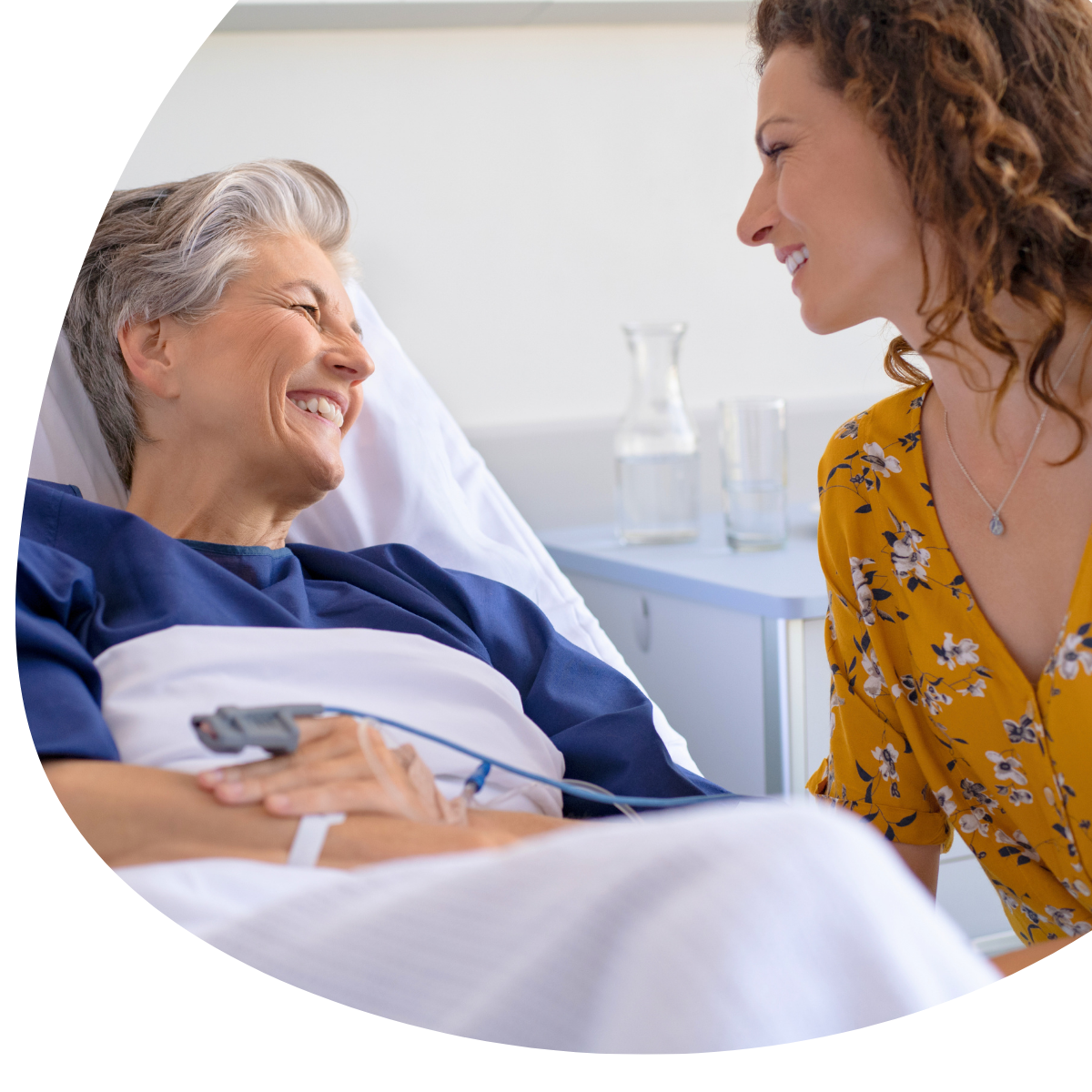 Hospital patient smiling and talking with a visitor at bedside