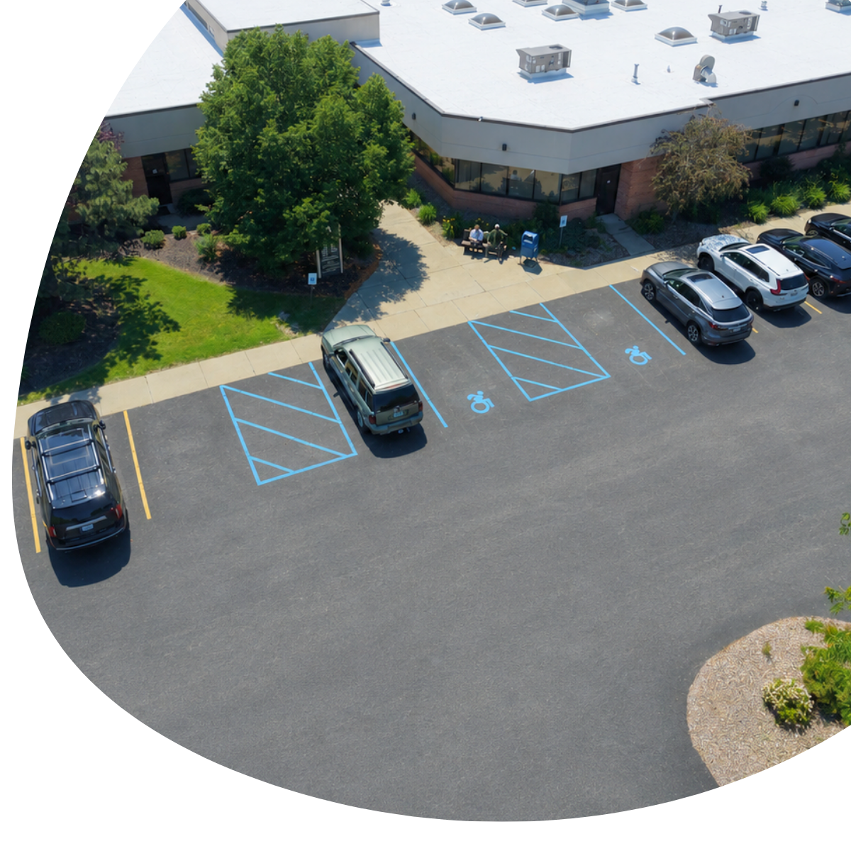Brick office building with a gray roof and three parked vehicles in the front lot.