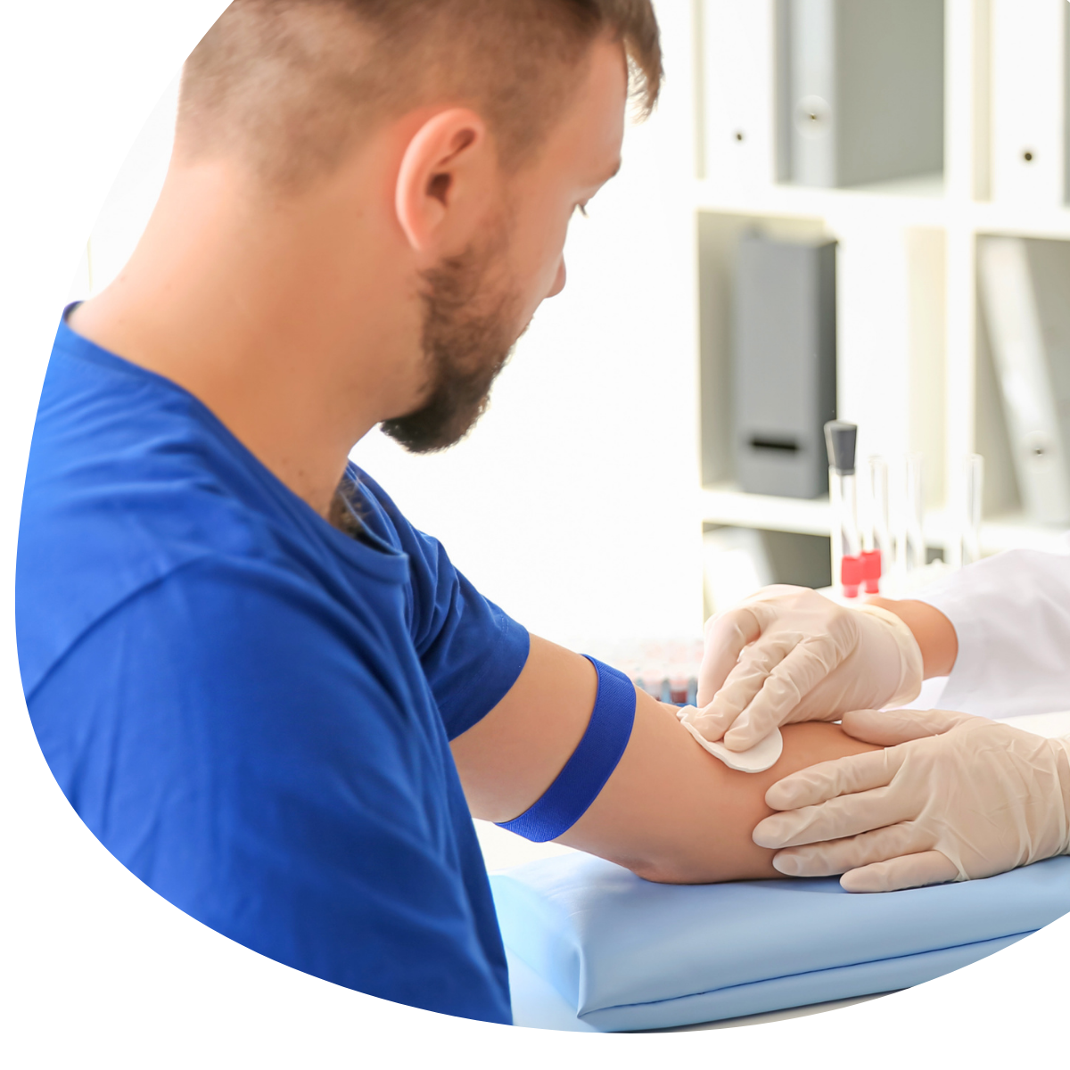 Nurse in white gloves drawing blood from a seated patient’s arm in a clinic