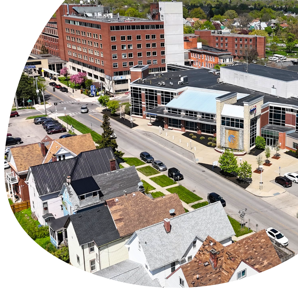 Brick office building with a gray roof and three parked vehicles in the front lot.