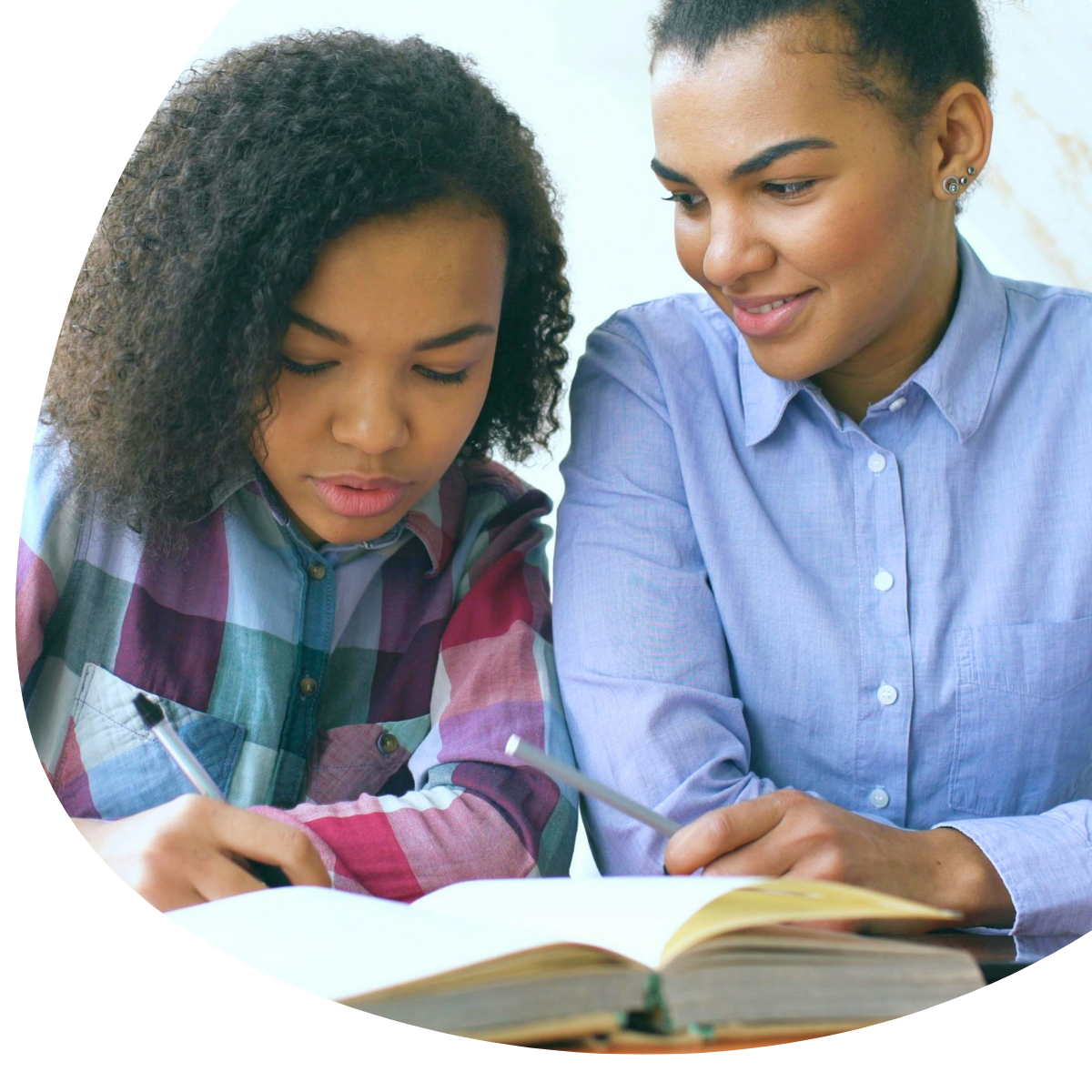 Two people reading a book together at a table, one pointing to the page