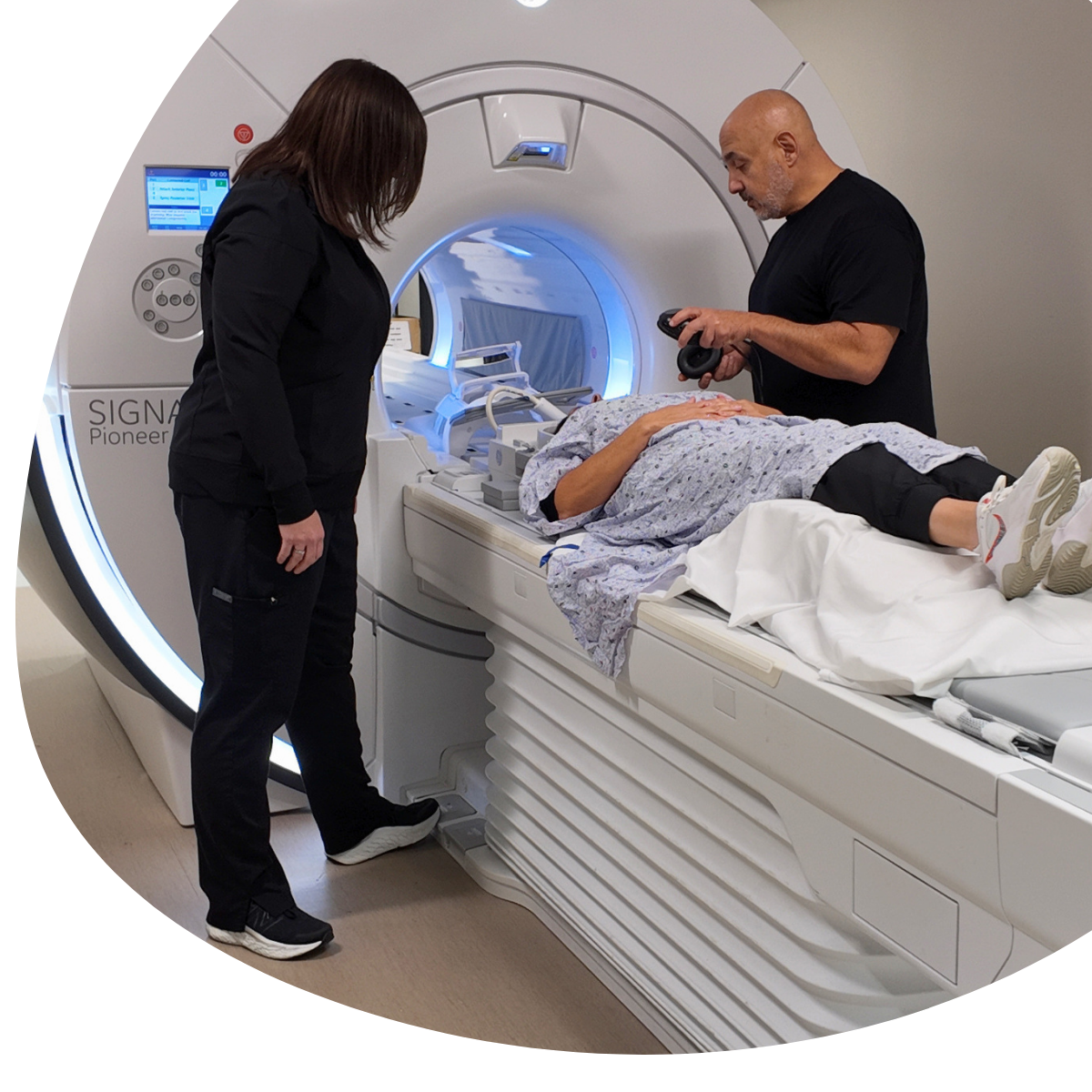 Technician and patient beside an MRI scanner in a medical imaging room
