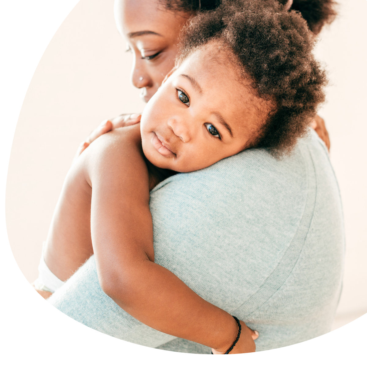 Adult hugging a smiling child, both in soft light against a pale background