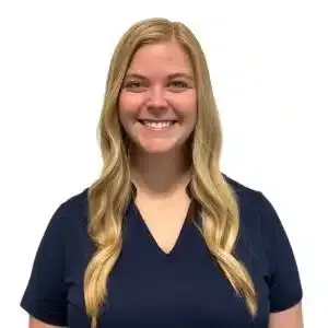 Smiling person with long blonde hair wearing a navy blue shirt on a white background