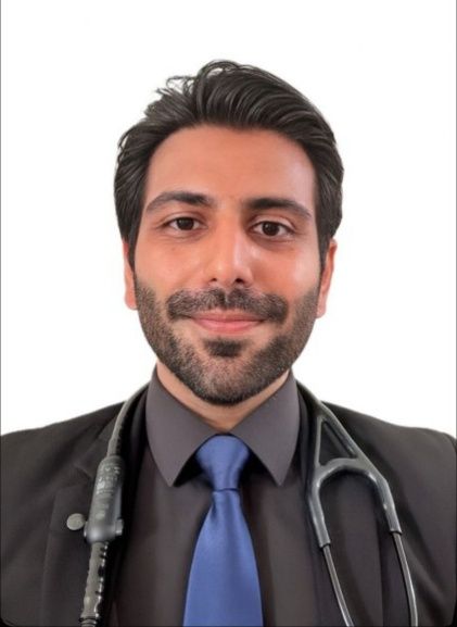 Portrait of a doctor in a black coat with a stethoscope and blue tie, smiling against a white background