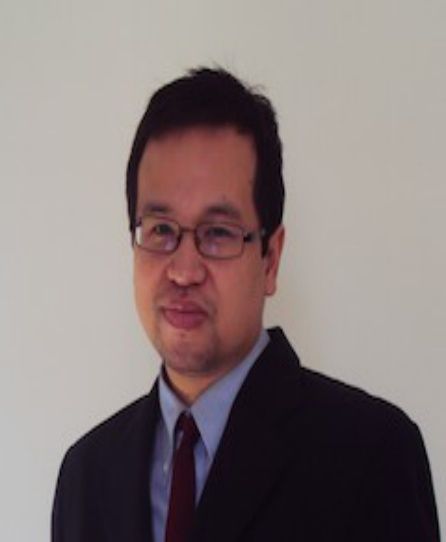 Portrait of a man in glasses and a dark suit against a plain light background