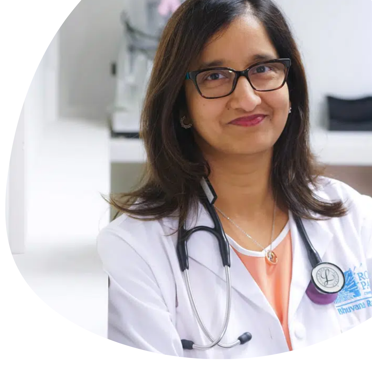Doctor in white coat with stethoscope, smiling in a bright clinic setting