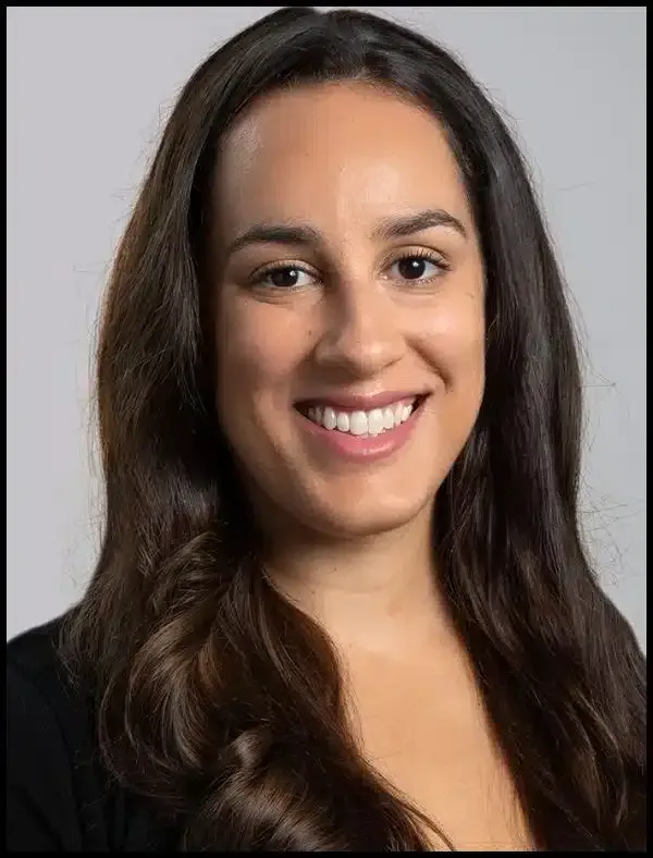 Smiling woman with long dark hair against a gray background
