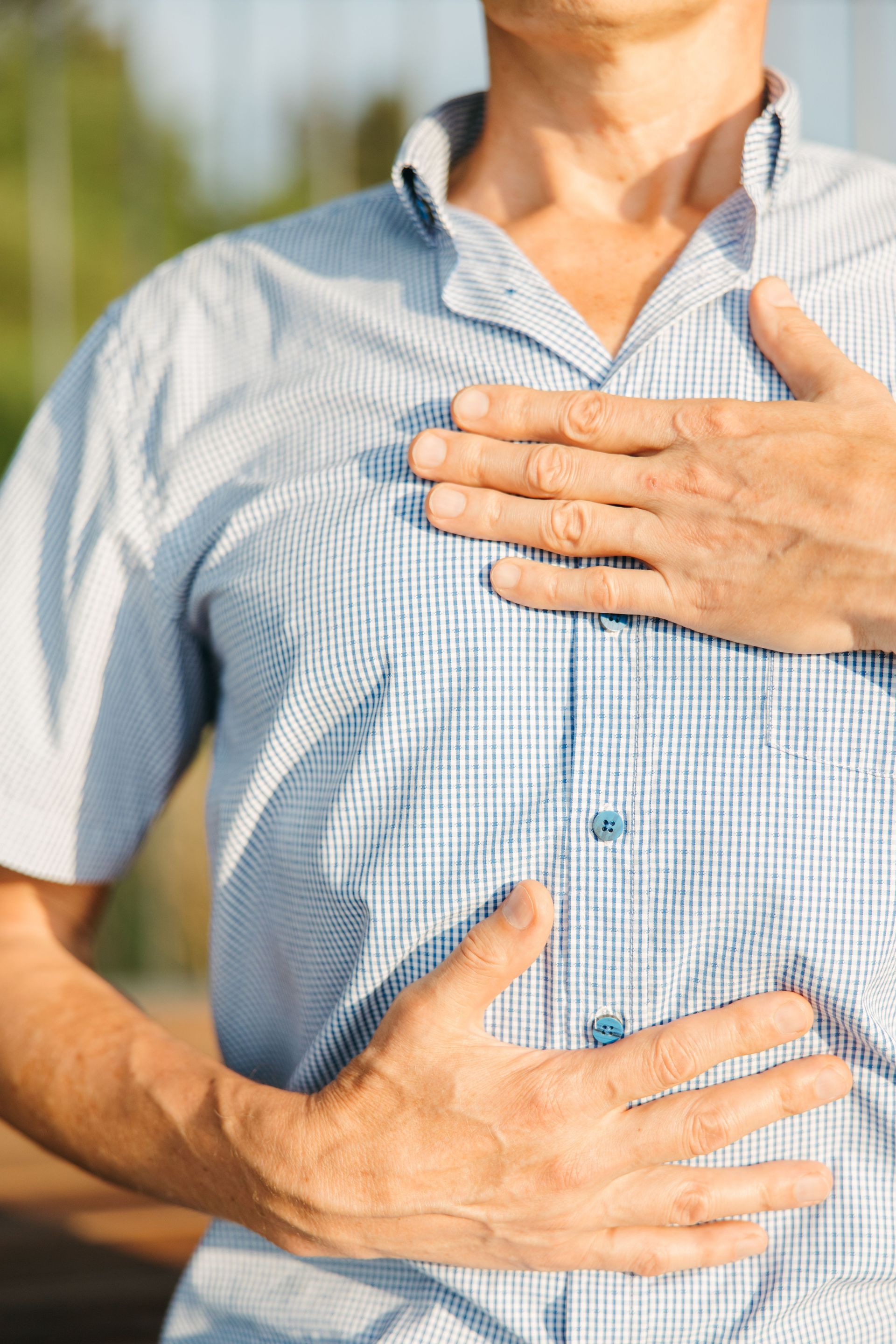 Person holding chest and stomach, suggesting chest discomfort or heartburn.
