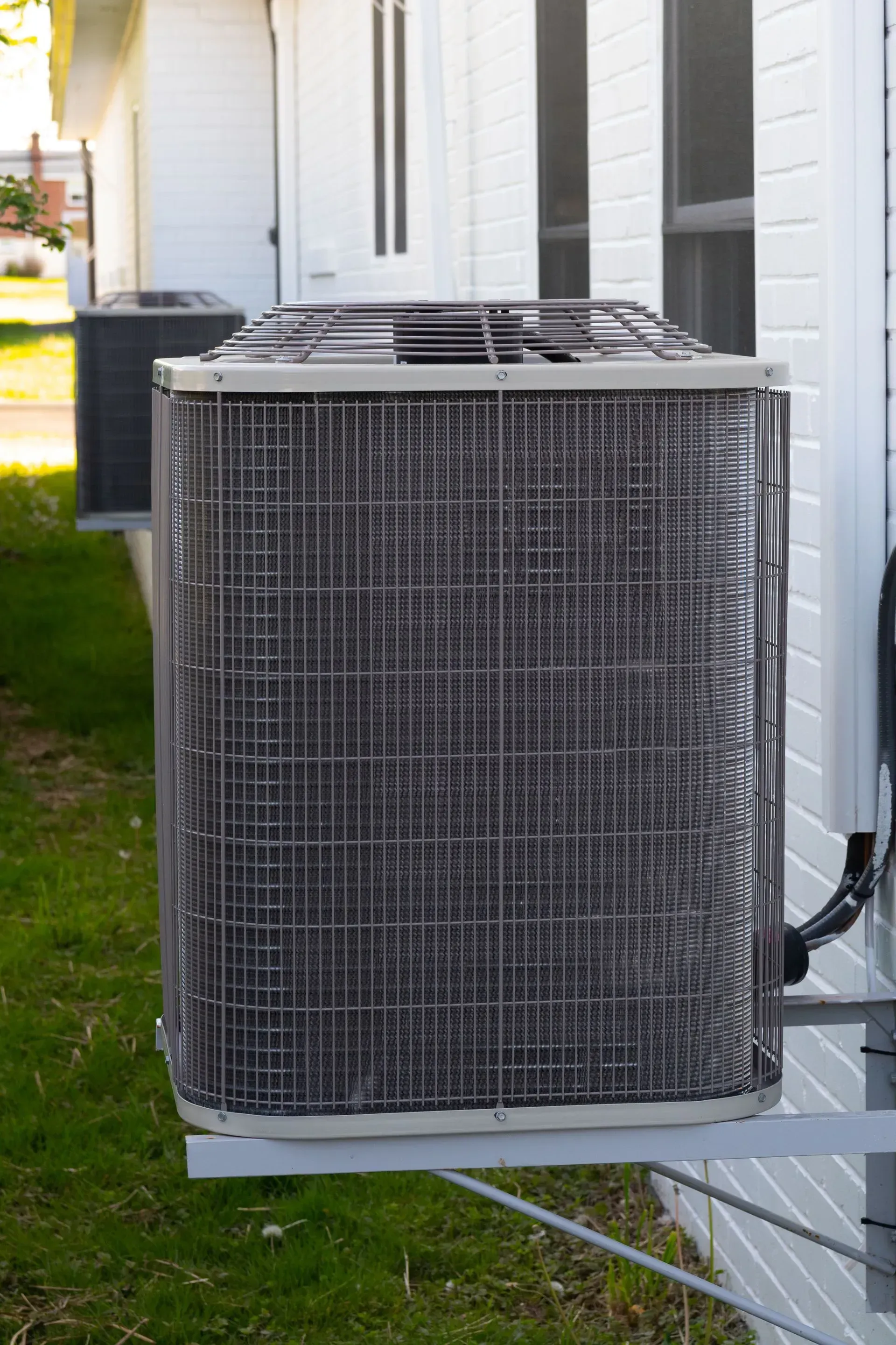 Outdoor air conditioning unit attached to a white building.