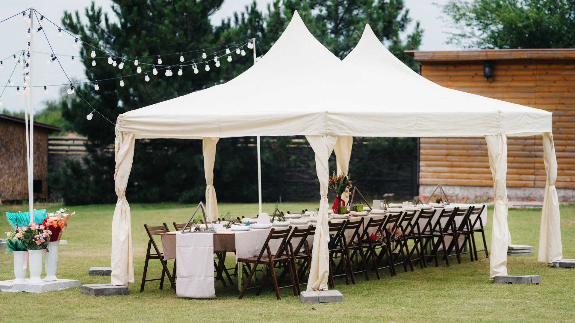 A white tent with tables and chairs underneath it in a field.